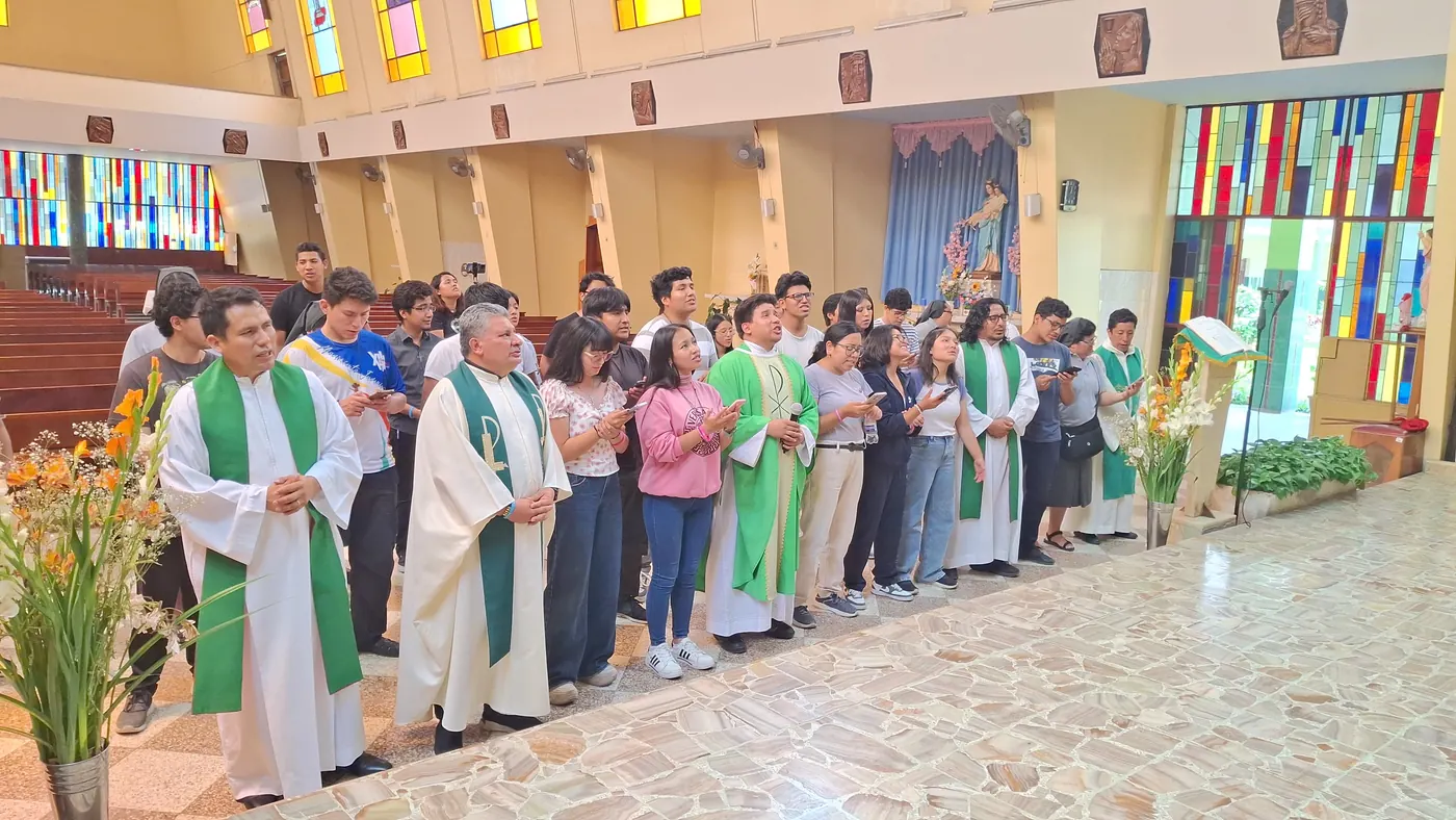 Grupo grande de jóvenes y salesianos reunidos en la capilla
